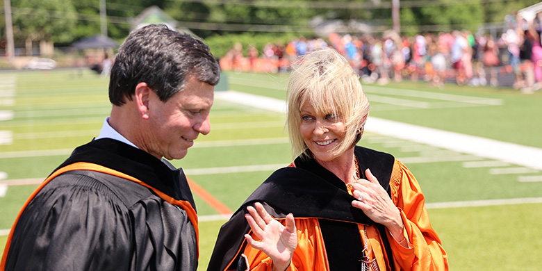 Frank Bisignano and Dr. Murray walking across the football field after commencement 2024