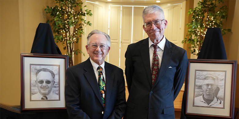 Dr. Roger Boyd and Dr. George Wiley standing next to their portraits for the Faculty Hall of Fame wall